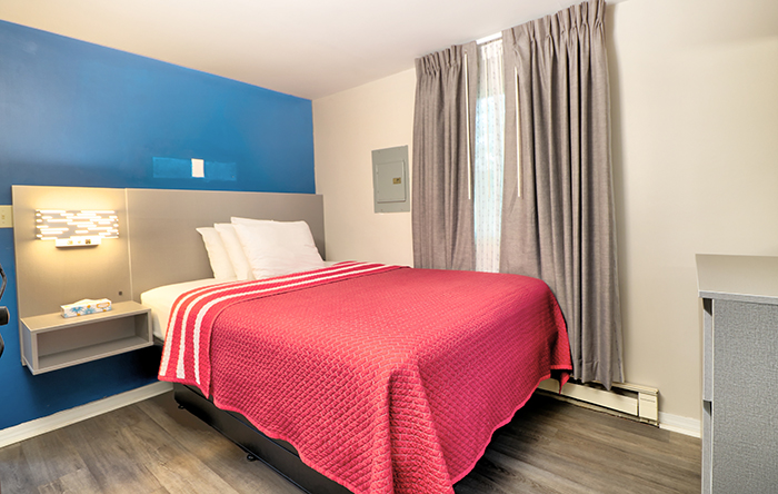 A hotel room with a bed, window, and nightstand.
