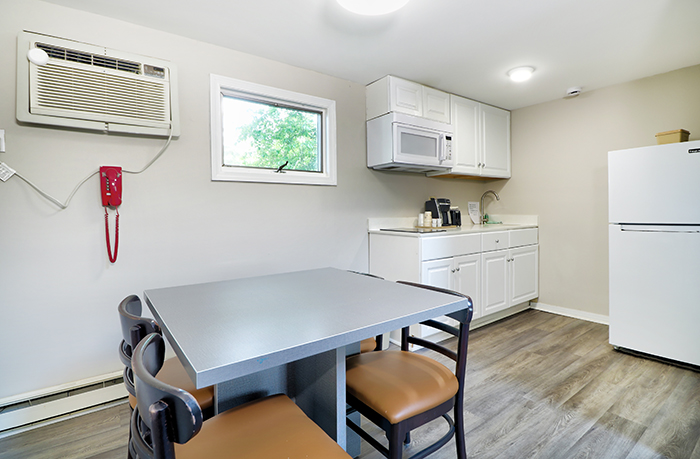 A small kitchenette with a table, chairs, microwave, and refrigerator.