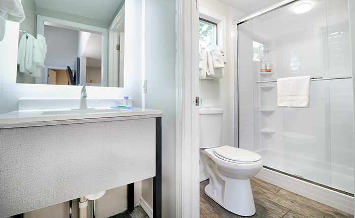 A clean and modern bathroom with a shower, toilet, sink, and mirror.